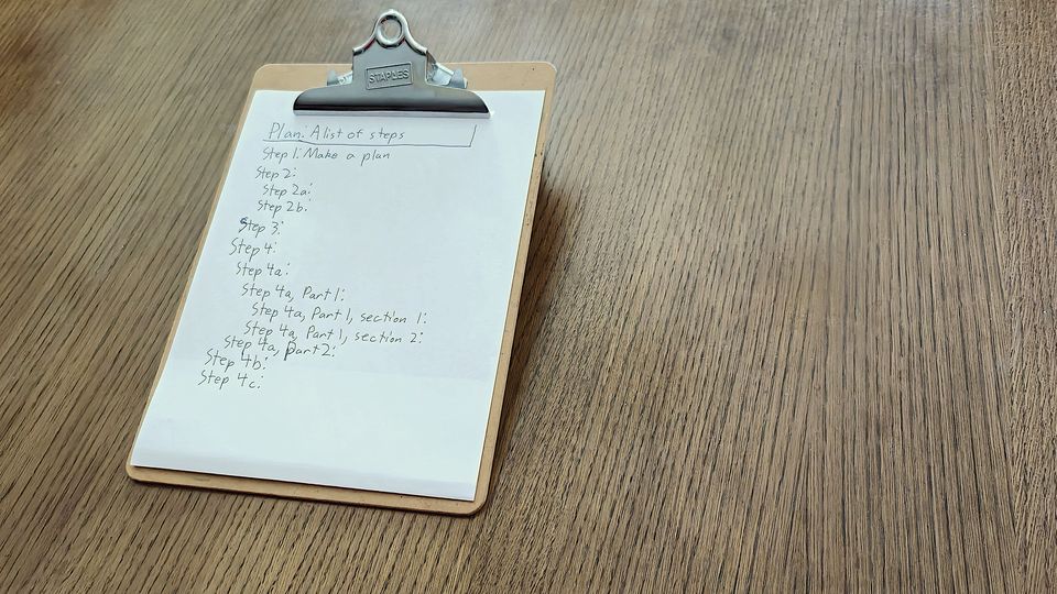 A clipboard holding a handwritten list on a wooden table