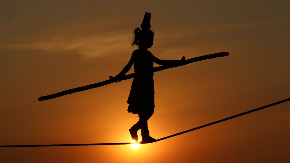 Silhouette of a tightrope walker crossing against a sunset