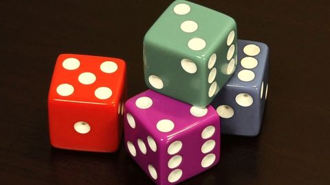 Colourful dice tumbling on a dark table
