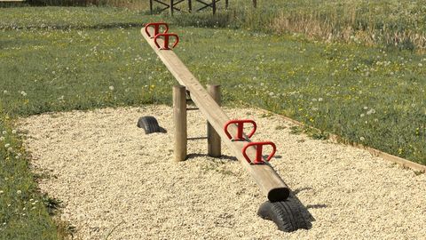 A wooden seesaw in an empty gravel playground