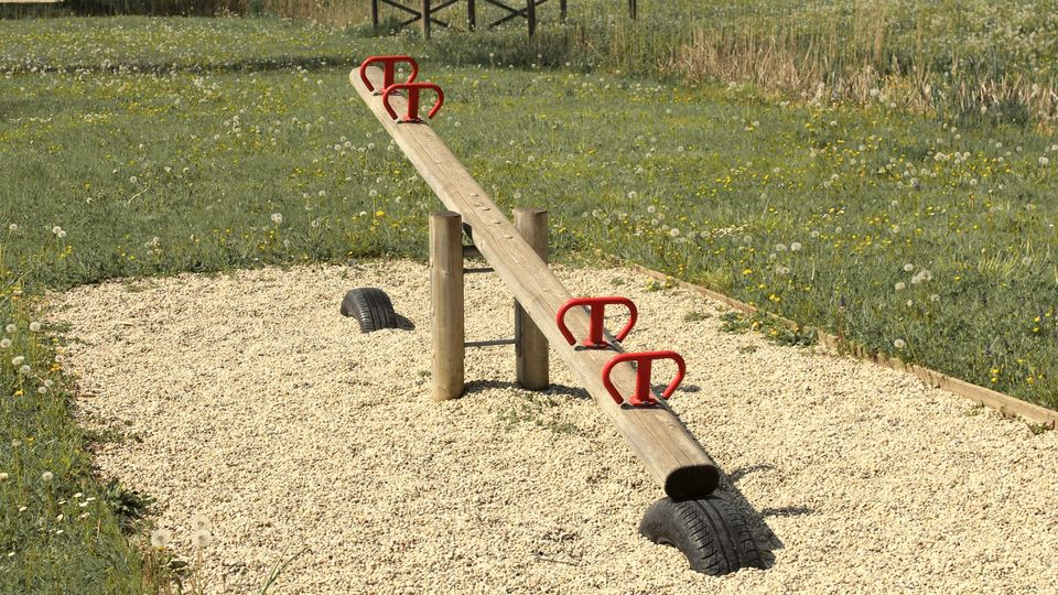A wooden seesaw in an empty gravel playground