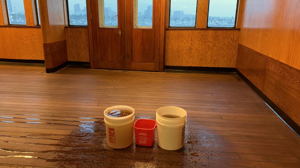 Small buckets on a wooden floor catching drips from a leak