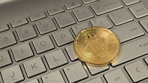 A gold-coloured physical bitcoin souvenir coin on a laptop keyboard