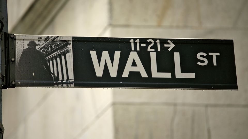 A Wall St street sign on the corner of a stone building