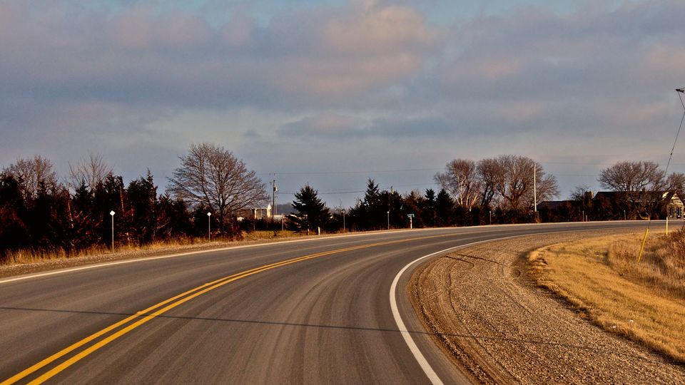 A road curving away towards the horizon at dusk