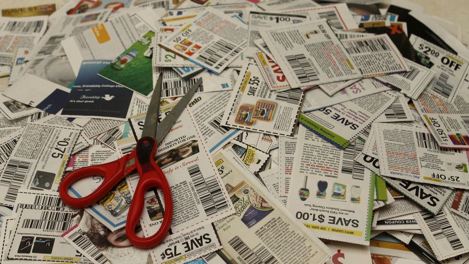 A pile of clipped paper coupons with a pair of scissors