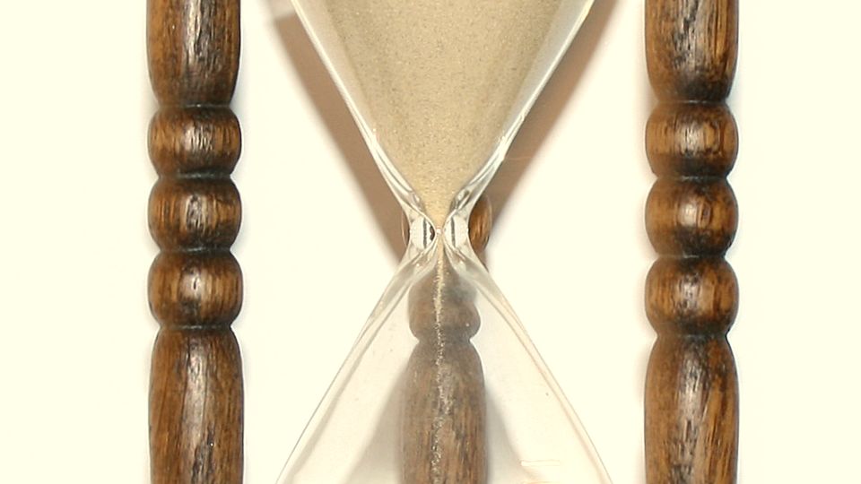 A wooden hourglass with sand running through