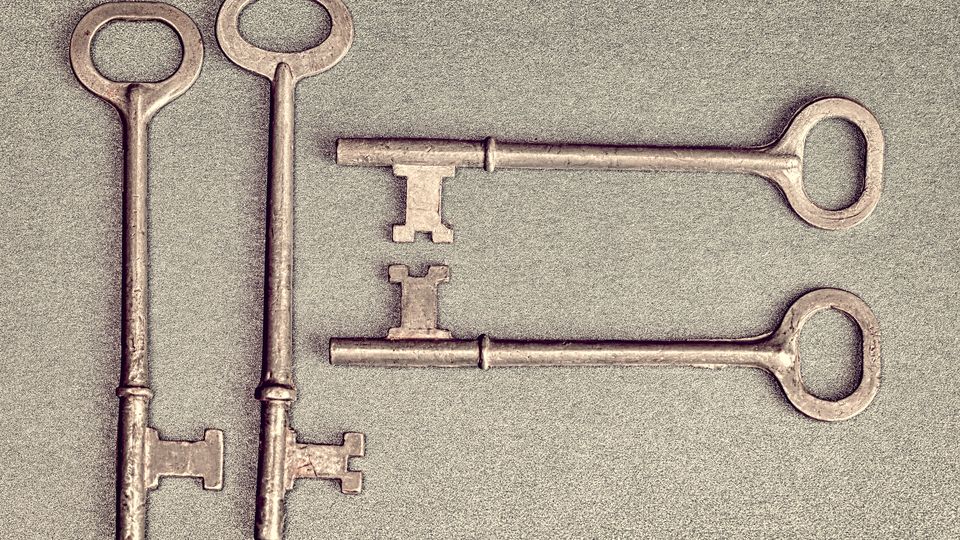 Antique iron skeleton keys laid on a grey surface