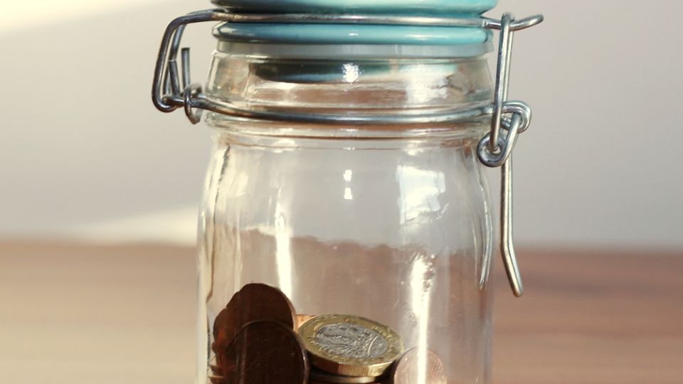 A glass jar with a few coins in it