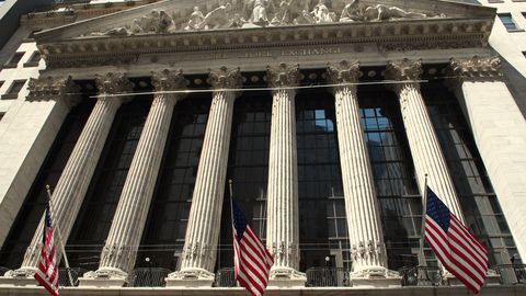 The columned facade of the New York Stock Exchange building hung with flags